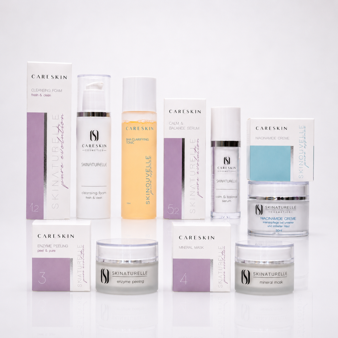 CARESKIN Hautpflegeset in einer hochwertigen Studioaufnahme auf weißem Hintergrund. Das Set umfasst Cleansing Foam, BHA Clarifying Tonic, Calm & Balance Serum, Enzyme Peeling, Mineral Mask und Niacinamide Creme mit ihren jeweiligen Verpackungen. Die Produkte sind harmonisch in zwei Reihen angeordnet und präsentieren das charakteristische CARESKIN-Design mit dezenten Flieder- und Türkisakzenten sowie einer leichten Spiegelung auf der glänzenden Oberfläche.